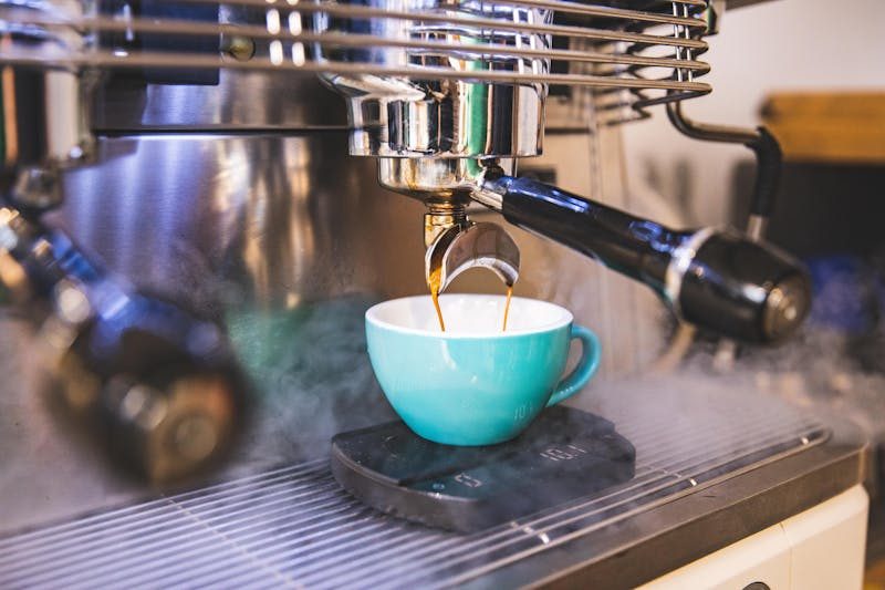 Close-up of espresso being made with a professional machine into a blue cup.